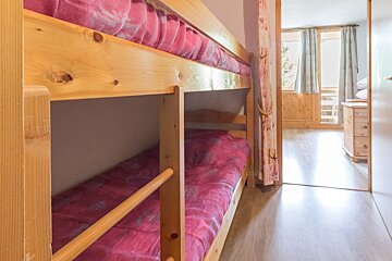 A wooden bunk bed with pink sheets in a bedroom