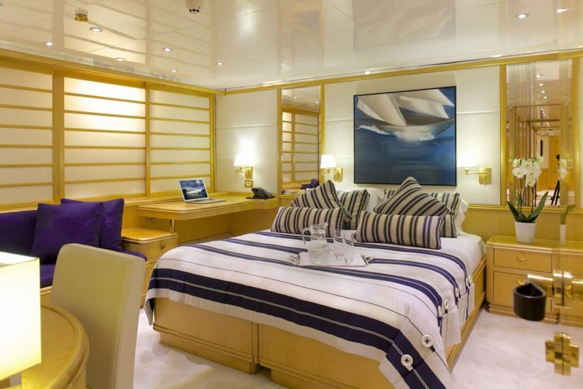 A bedroom with a large bed and a laptop on the desk