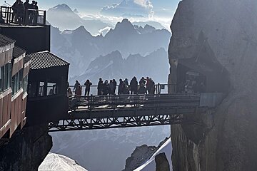 A group of people standing on a bridge with mountains in the background