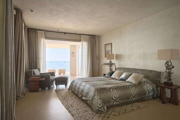 A bedroom with a large bed and a view of the ocean