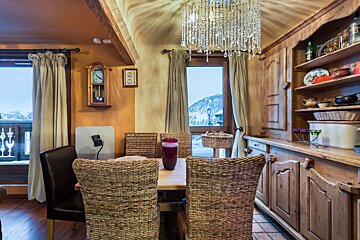 A dining room with wicker chairs and a clock on the wall