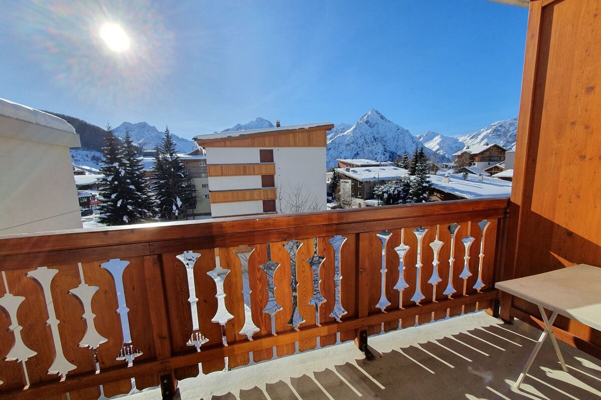 A balcony with a view of snowy mountains and buildings