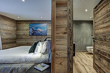A bedroom with a painting on the wall above the bed
