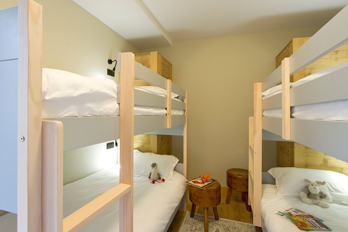 A bedroom with bunk beds and a book on a stool