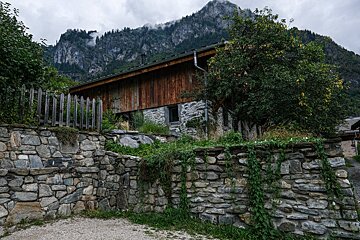A stone wall surrounds a house with a mountain in the background