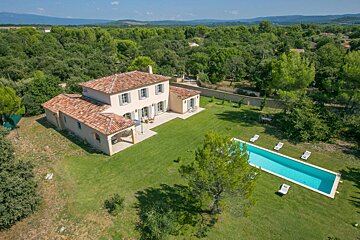 An aerial view of a house with a large swimming pool