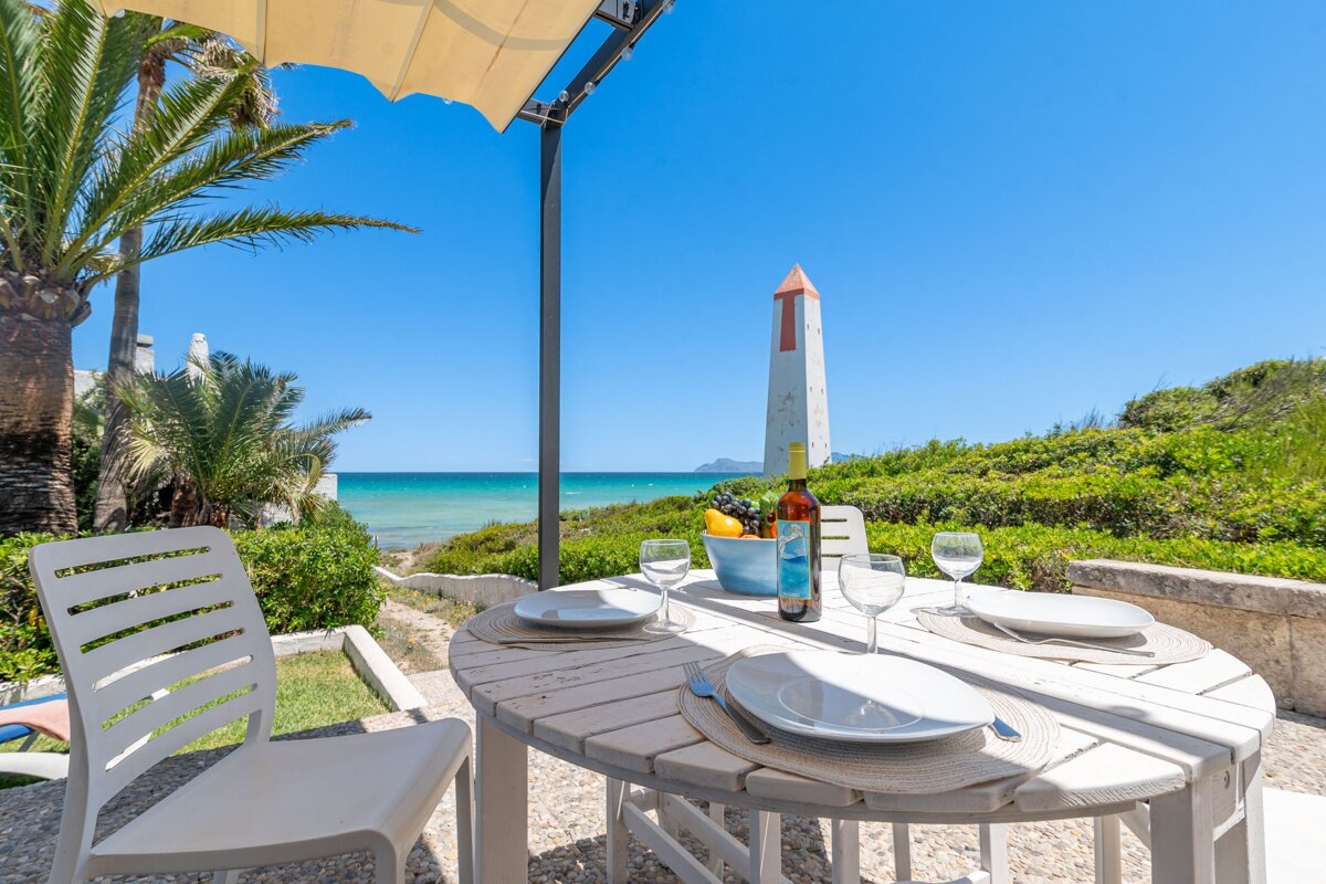 A bottle of wine sits on a table in front of the ocean