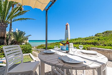 A bottle of wine sits on a table in front of the ocean