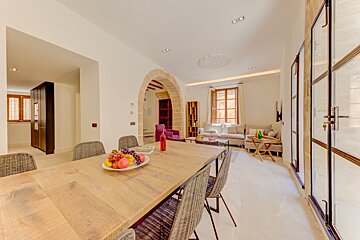 A dining room table with a bowl of fruit on it