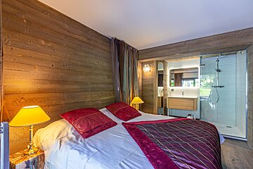A bedroom with a large bed and two lamps