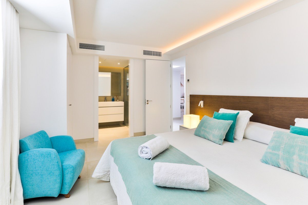 A bedroom with a large bed and a blue chair