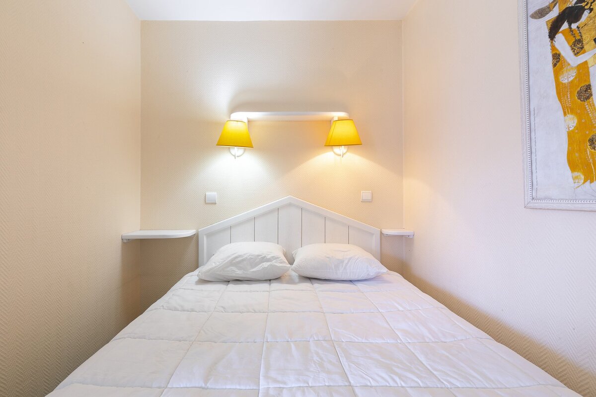 A bedroom with a bed and two lamps on the wall