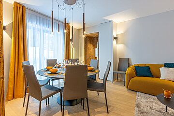 A dining room with a table and chairs and a yellow couch