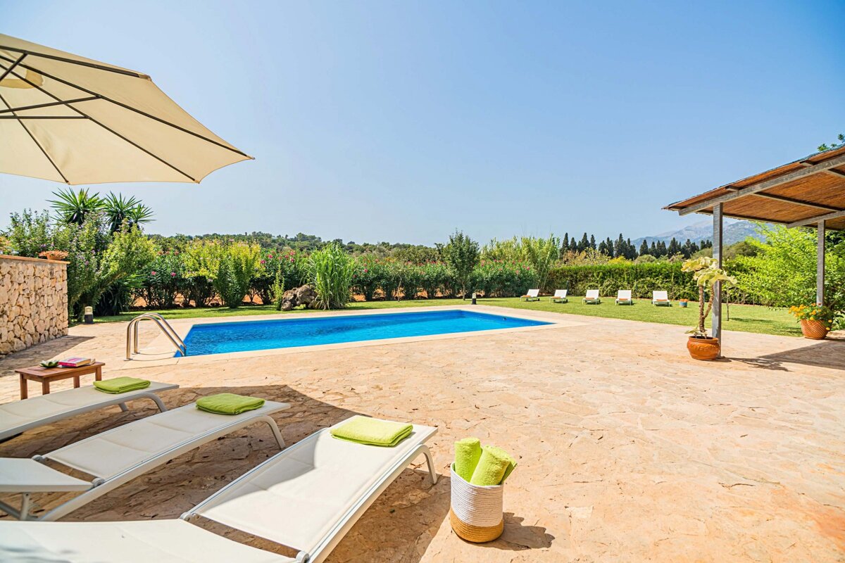 A large swimming pool is surrounded by chairs and umbrellas