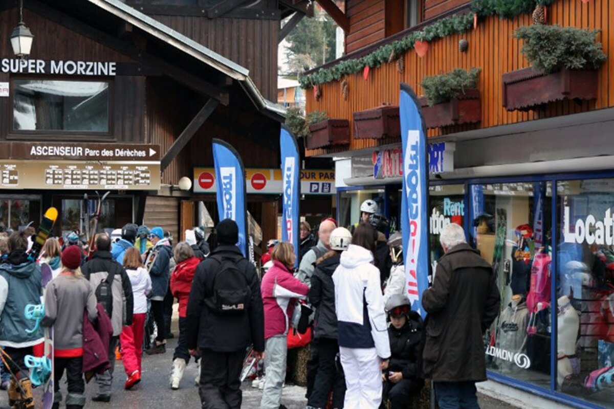 A group of people walking in front of a store called super morzine