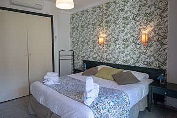 A hotel room with a bed and a wall with leaves on it