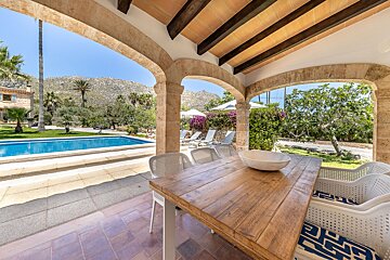 A wooden table with a bowl on it sits in front of a swimming pool
