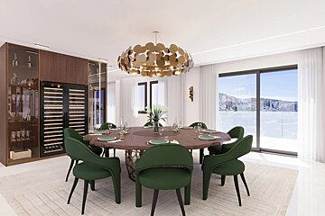Modern dining room featuring a round wooden table with green chairs, a gold chandelier, and a large window overlooking a scenic view.