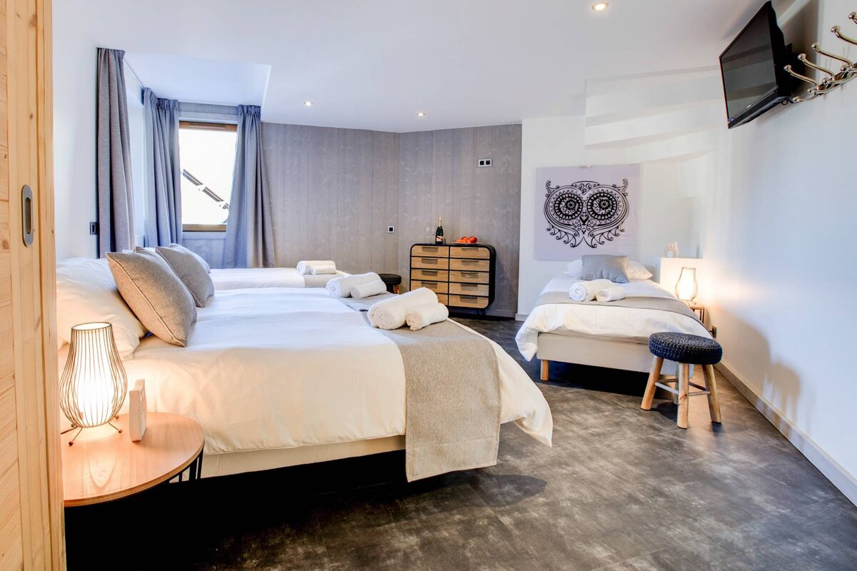 A bedroom with three beds and a painting of an owl on the wall