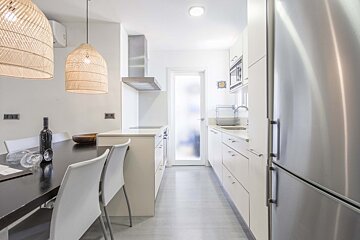 A kitchen with white cabinets and a stainless steel refrigerator