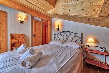 A bedroom with a bed and a nightstand with a clock on it