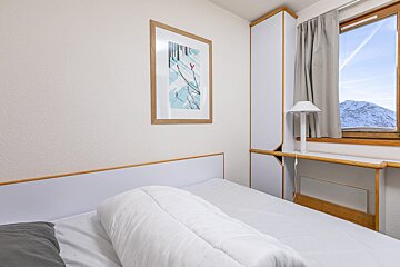 A bedroom with a picture on the wall above the bed