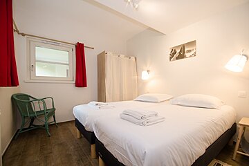 A bedroom with two beds and a green chair