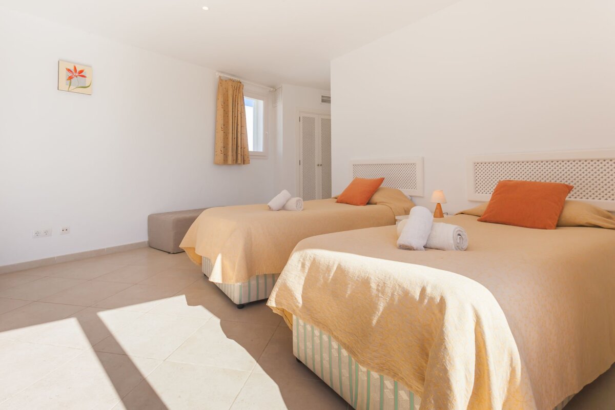 A bedroom with two beds and a picture of a flower on the wall