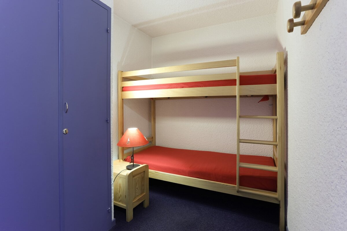 A bunk bed with red sheets and a lamp
