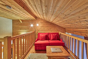 A wooden staircase with a red couch and a laptop on a table