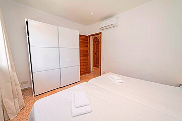 A bedroom with two beds and a sliding wardrobe