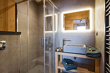 A bathroom with a walk in shower and a sink