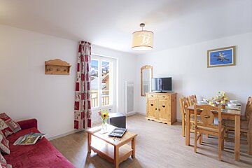 A living room with a red couch and a table and chairs
