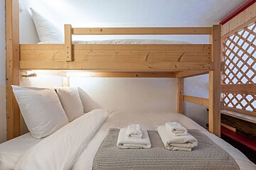 A bunk bed with white sheets and towels on it