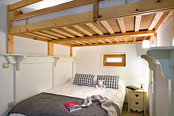 A small bedroom with a bunk bed and a book on the bed