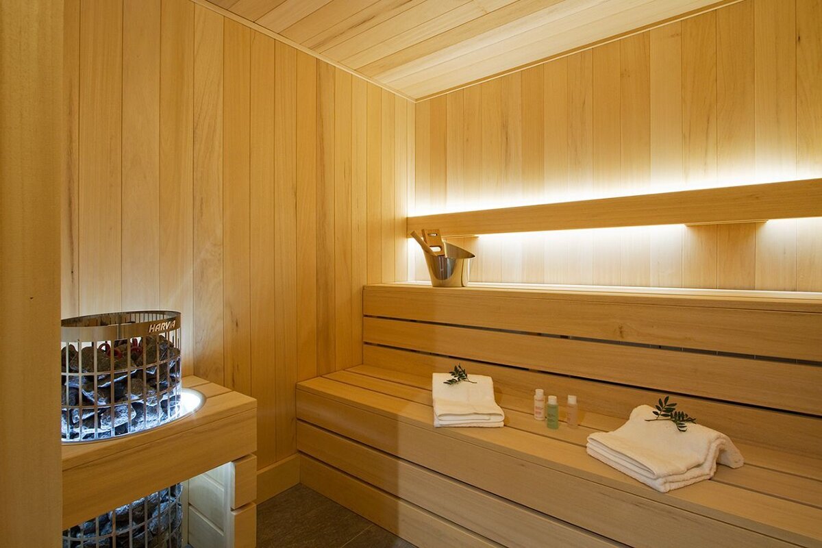 A wooden sauna with a bucket and towels on the bench