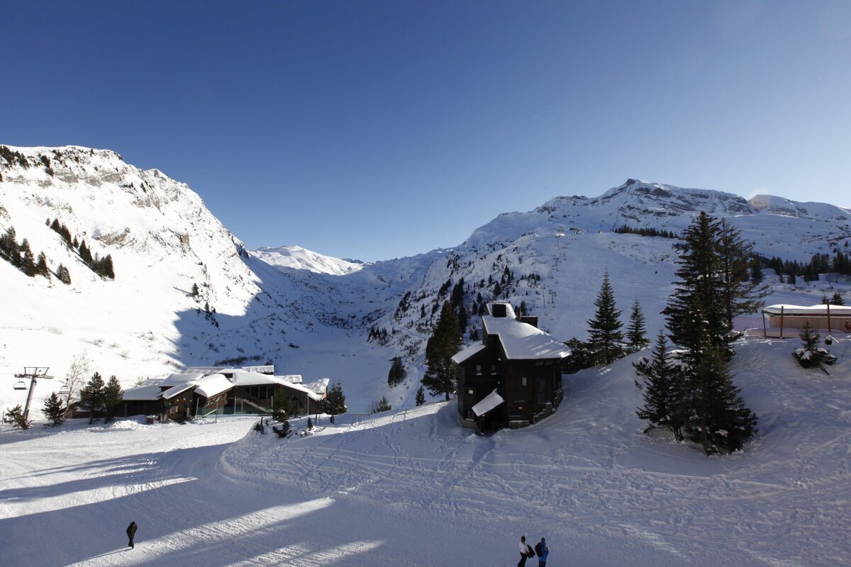 A snowy mountain landscape with a small house in the foreground