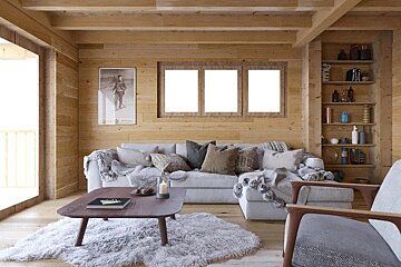 A rustic and cozy living room with wooden paneled walls, a large gray sectional sofa, a fluffy rug, coffee table, and built-in shelves.