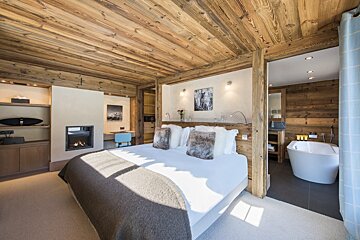 A bedroom with a large bed and a bathtub