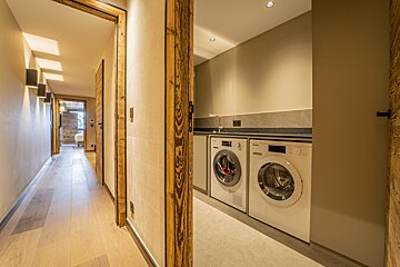 A rustic modern hallway with wood floors and trim, looking into a laundry alcove with a washing machine and dryer.