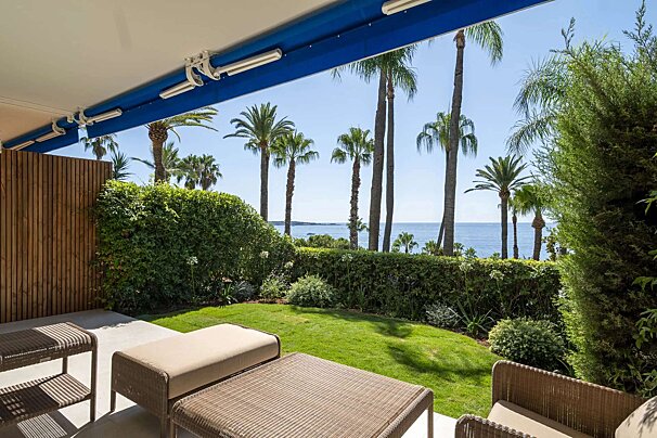 A patio with a view of the ocean and palm trees