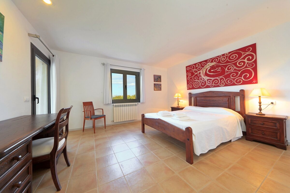 A bedroom with a bed a desk and two lamps