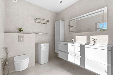 Sunny, modern bathroom with light grey tiles, a floating toilet, double vanity, white storage cabinets, and a large mirror.