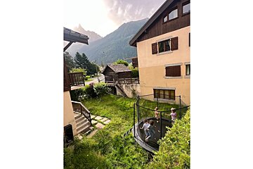 A group of people are playing on a trampoline in front of a house