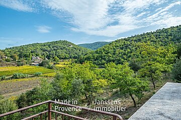 Made in provence by janssens immobilier is written on a balcony overlooking a lush green hillside