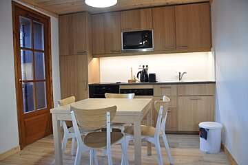 A kitchen with a table and chairs and a trash can