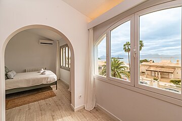 A bedroom with a view of the ocean and palm trees