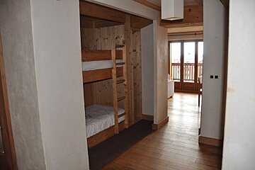 A room with bunk beds and a balcony in the background