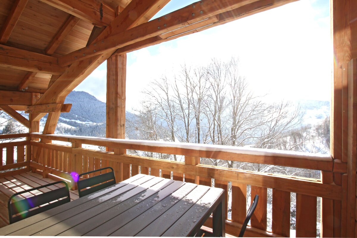 A balcony with a table and chairs and a view of snowy mountains