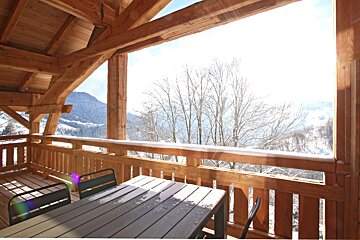 A balcony with a table and chairs and a view of snowy mountains